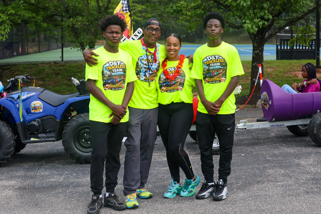 D&T Trackless Train team posing together in neon green event shirts at a community event