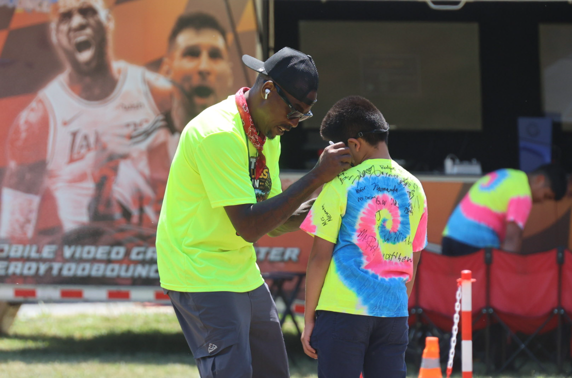 D&T host signing a child's shirt at an outdoor event