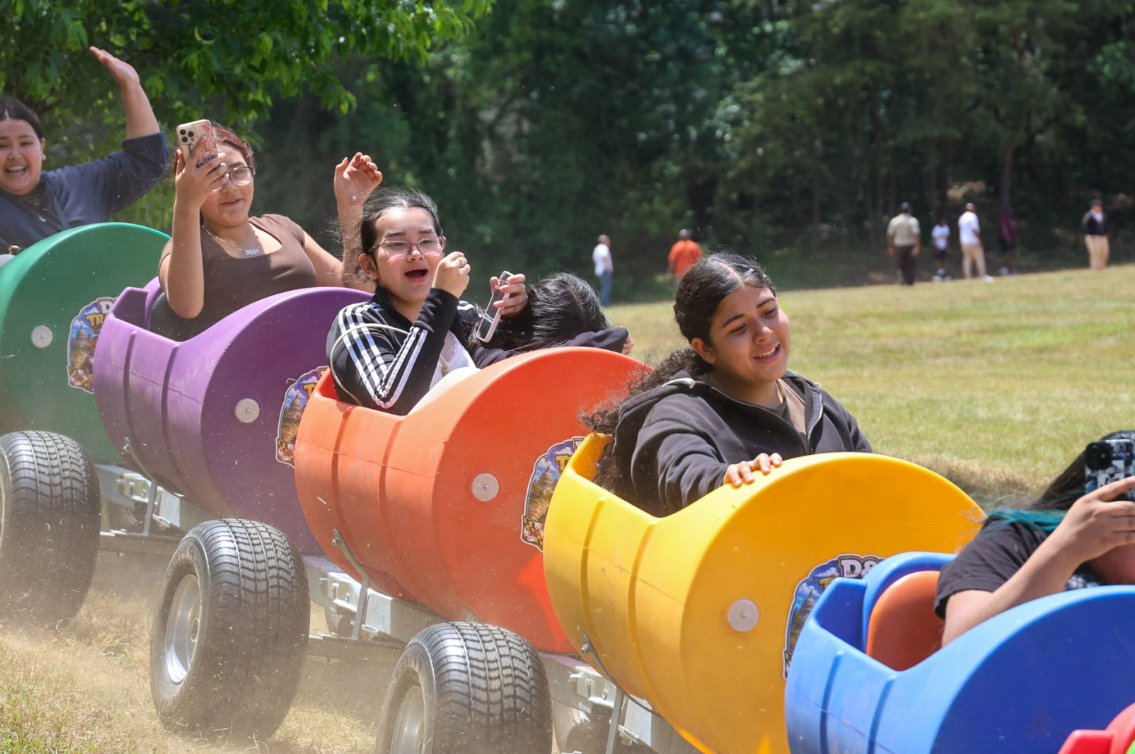 Teens laughing and cheering on the D&T trackless train ride at a community event
