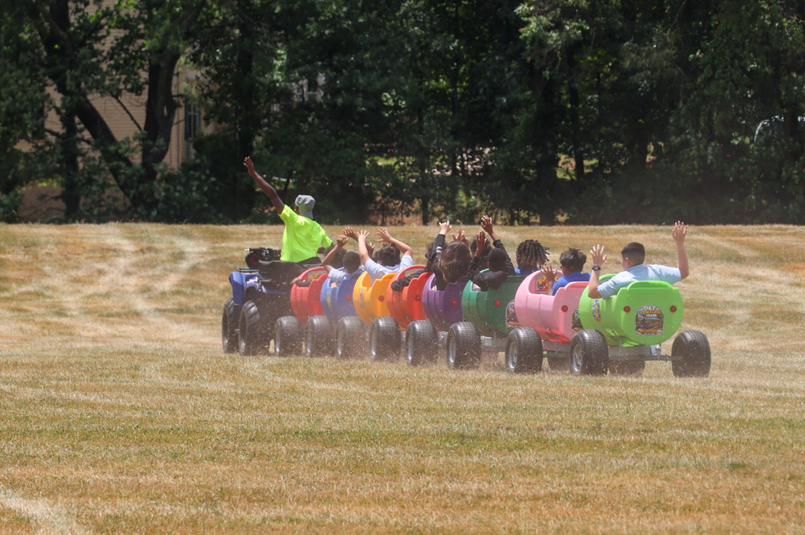 Children enjoying a colorful trackless train ride across a grassy field